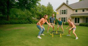 Familia jugando a Spikeball en el jardín de casa con entusiasmo